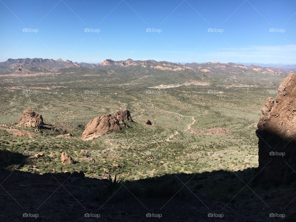 View from a desert mountain; tiny trail visible and beautiful blue skies