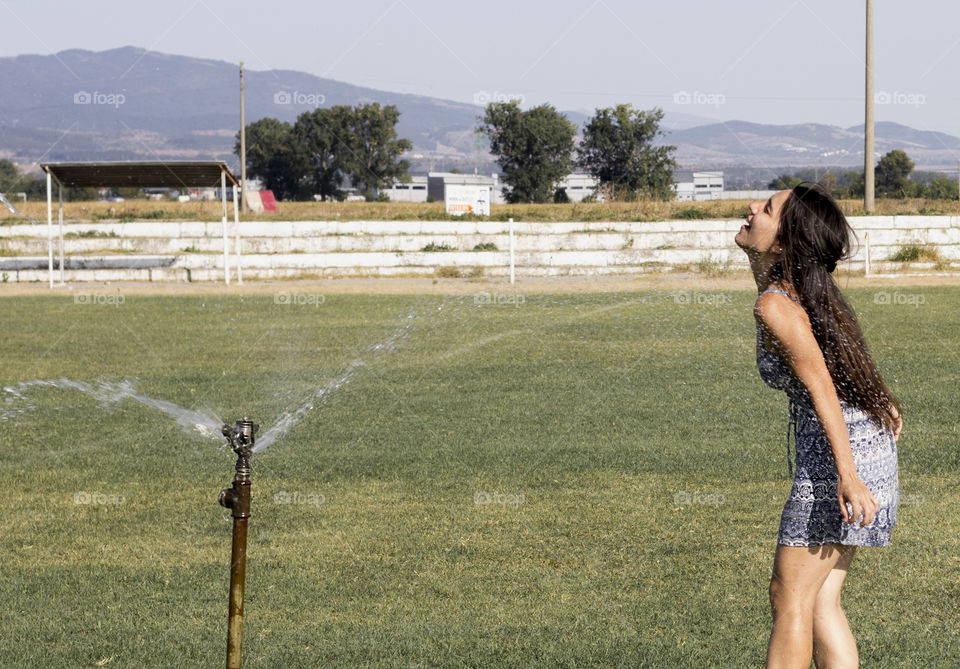 Beautiful woman and sprikler on stadium, splash of water