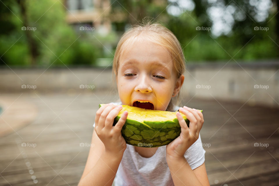 Happy kid eating watermelon at summer 