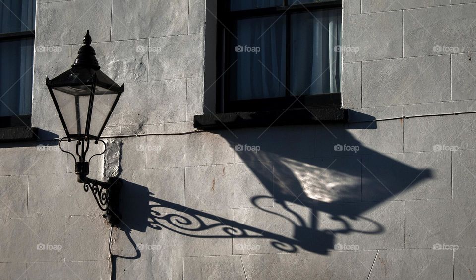 Long shadow of a Georgian style street lamp under a window