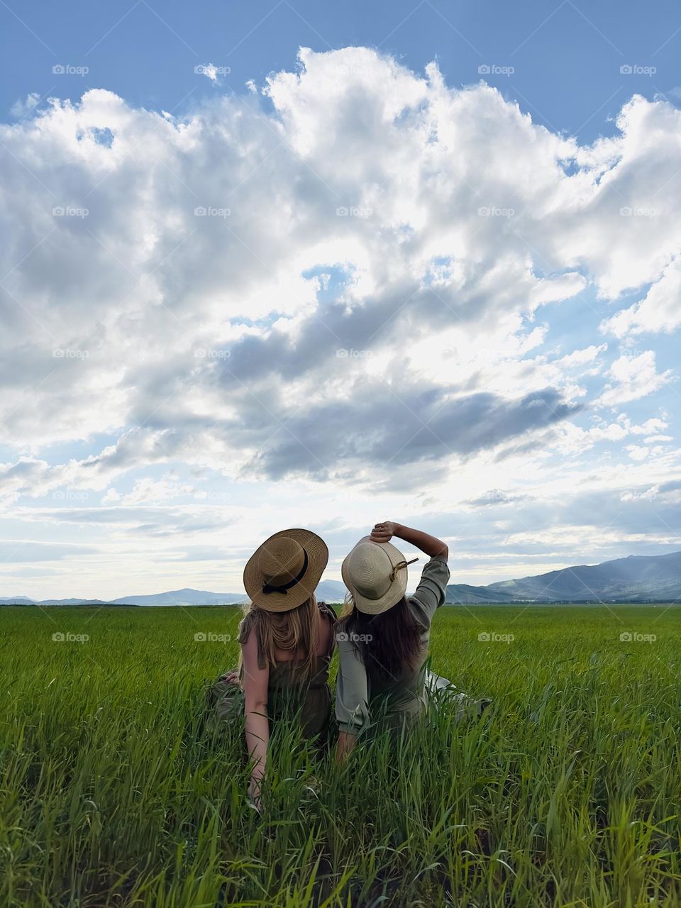 two girls sisters on a picnic in a field looking at the sky