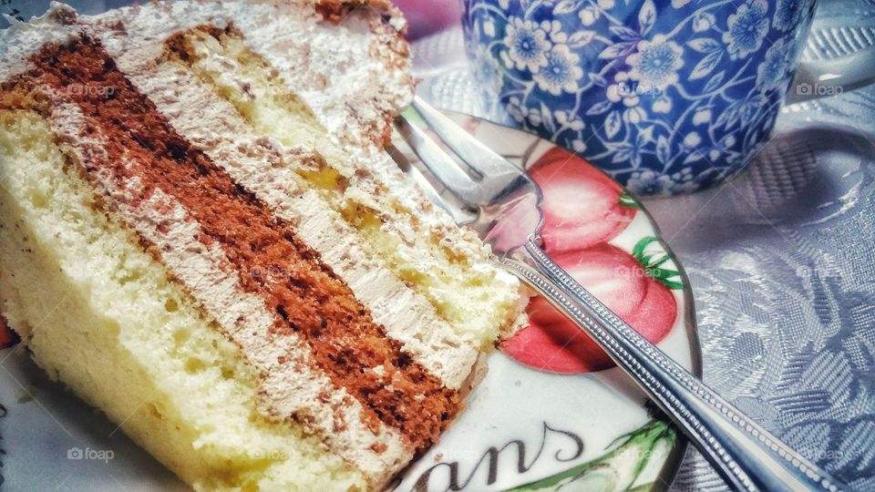 A slice of birthday cake on a serving plate. The cake is composed of layers of vanilla and chocolate slices, interspersed and covered with fresh cream.