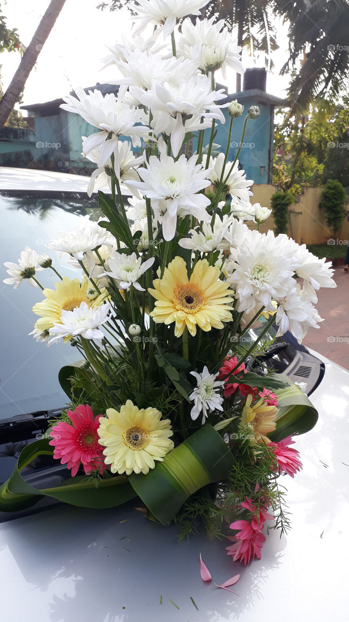 Just Marriaged couple’s car decorated with  Flowers on top of the car