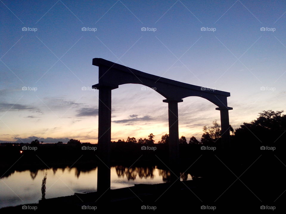 Silhouette of arch with calm river
