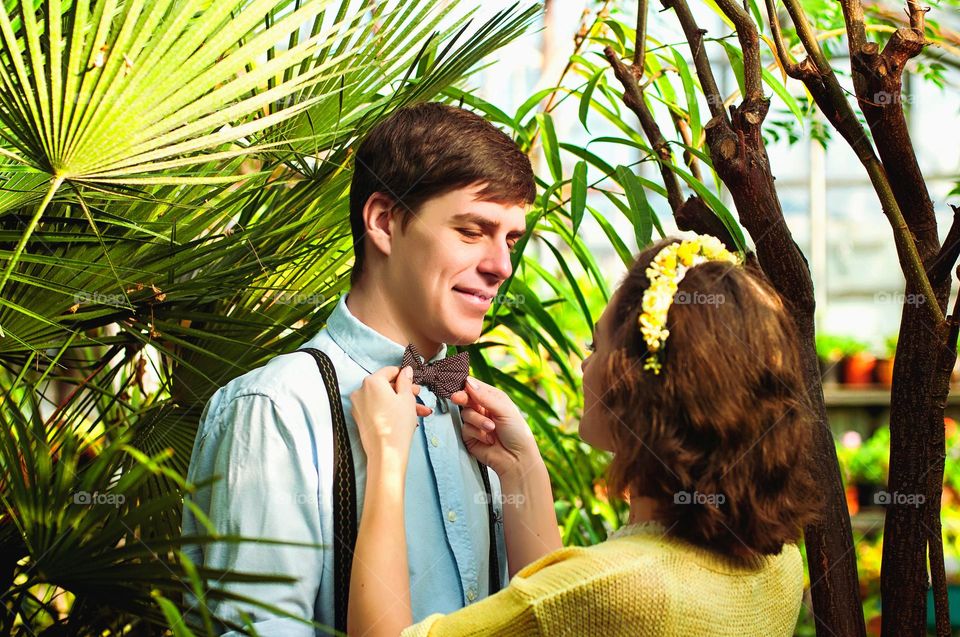 Lifestyle love story, small wedding of beautiful, happy young couple in glass greenhouse in spring.  Kiss, hugs, love