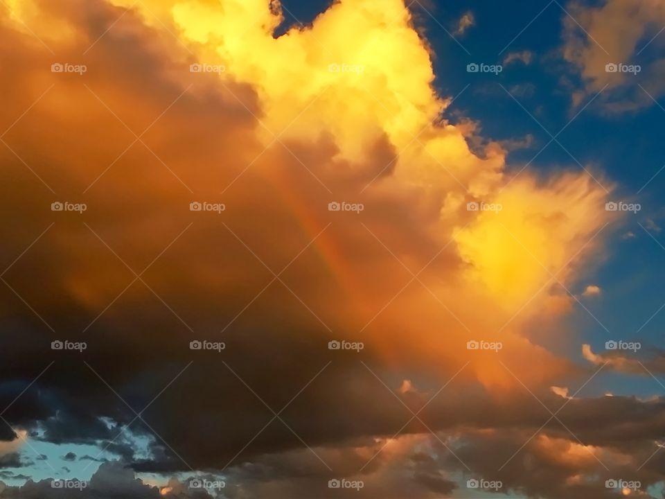 Rainbow in a fiery storm cloud at sunset