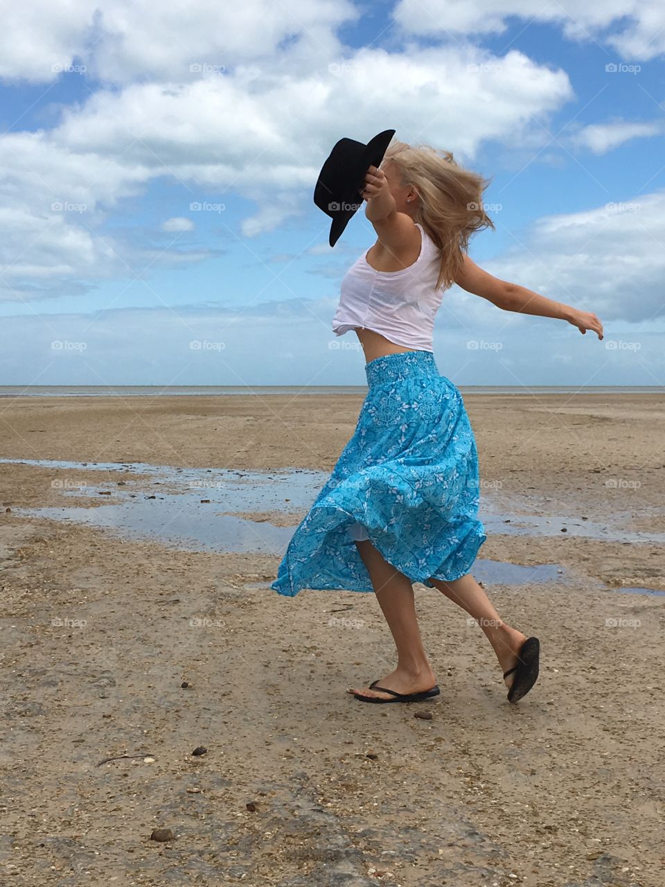 FRE form artistic expressive dance on the beach by young blonde woman in long flowing skirt and black hat