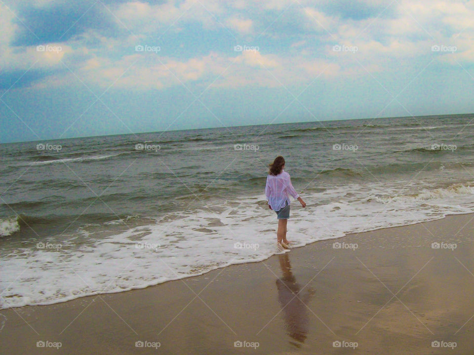 girl walking on the beach in a white shirt