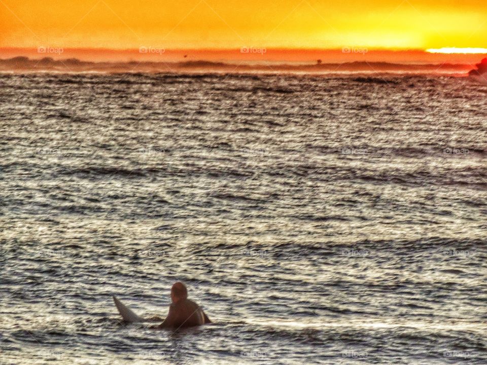 Surfing At Sunset. Surfer In The Water During The Golden Hour
