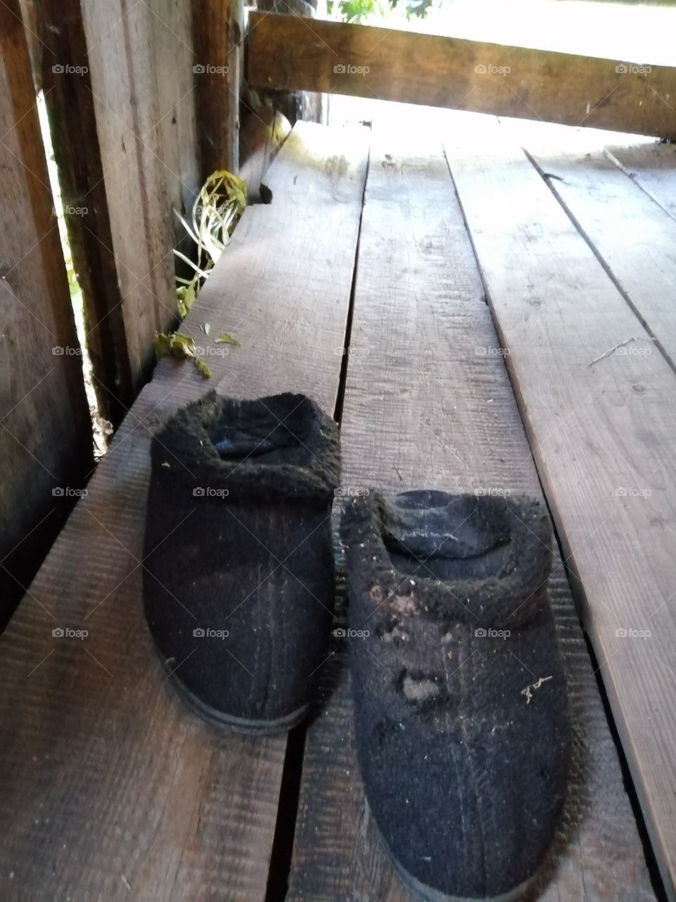 Old black uggs trampled on the floor of untreated boards