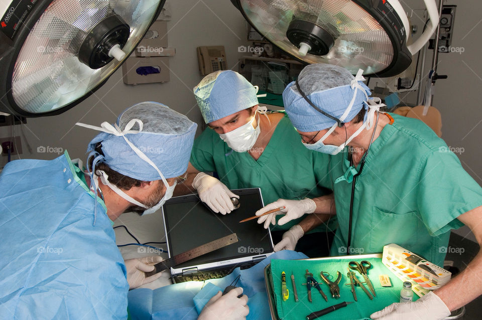 Three men operate on a computer in the emergency room at the hospital