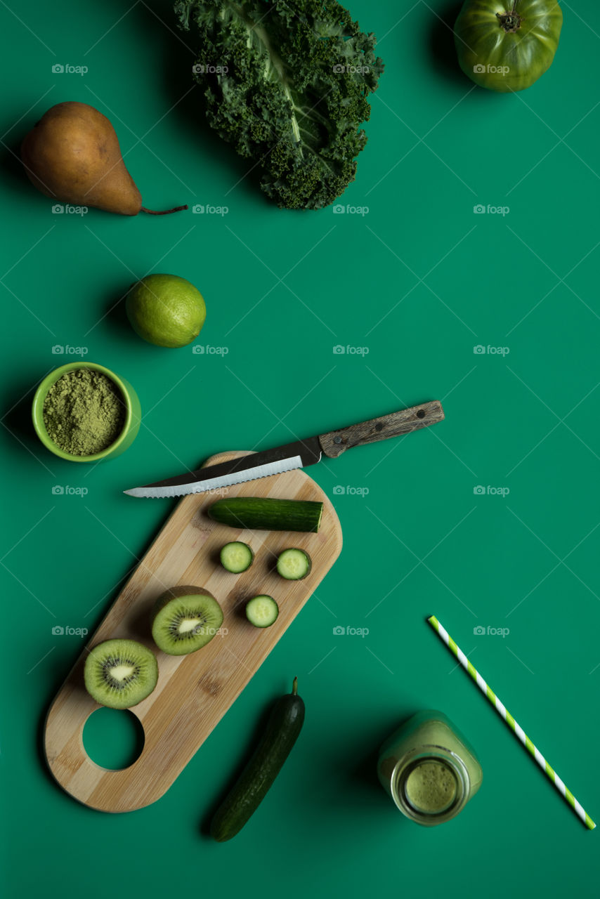 Monochromatic green flat lay of a vegetable smoothie and ingredients 