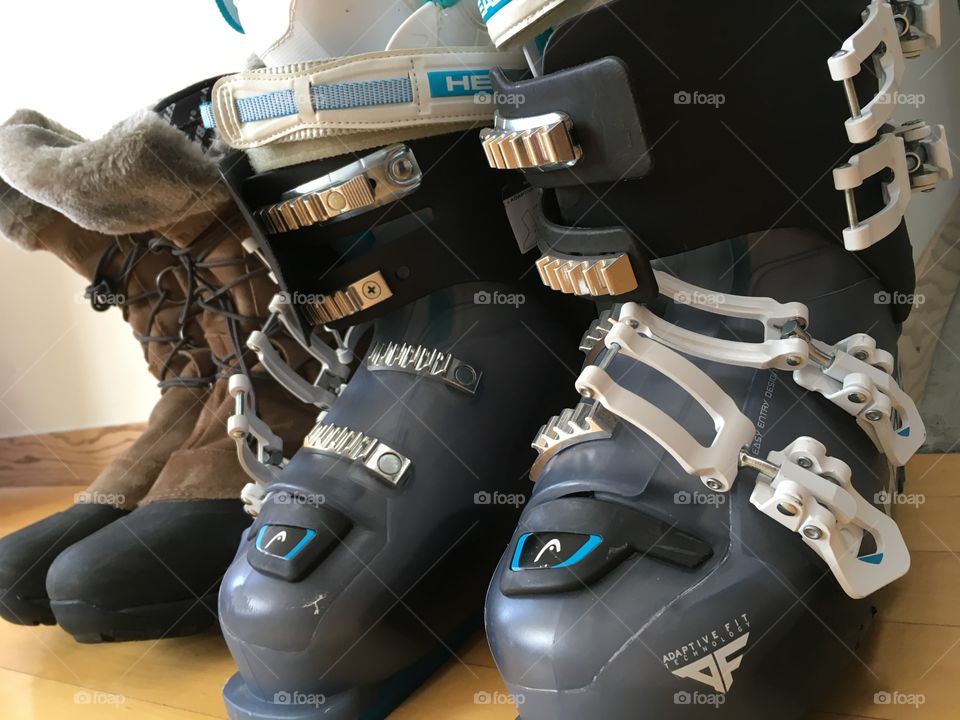 Blue and grey ski boots and snow boots against the wall 