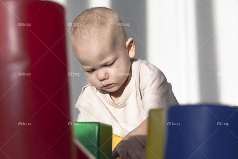 The little boy is focused on the construction of multi-colored pyramids and cubes.