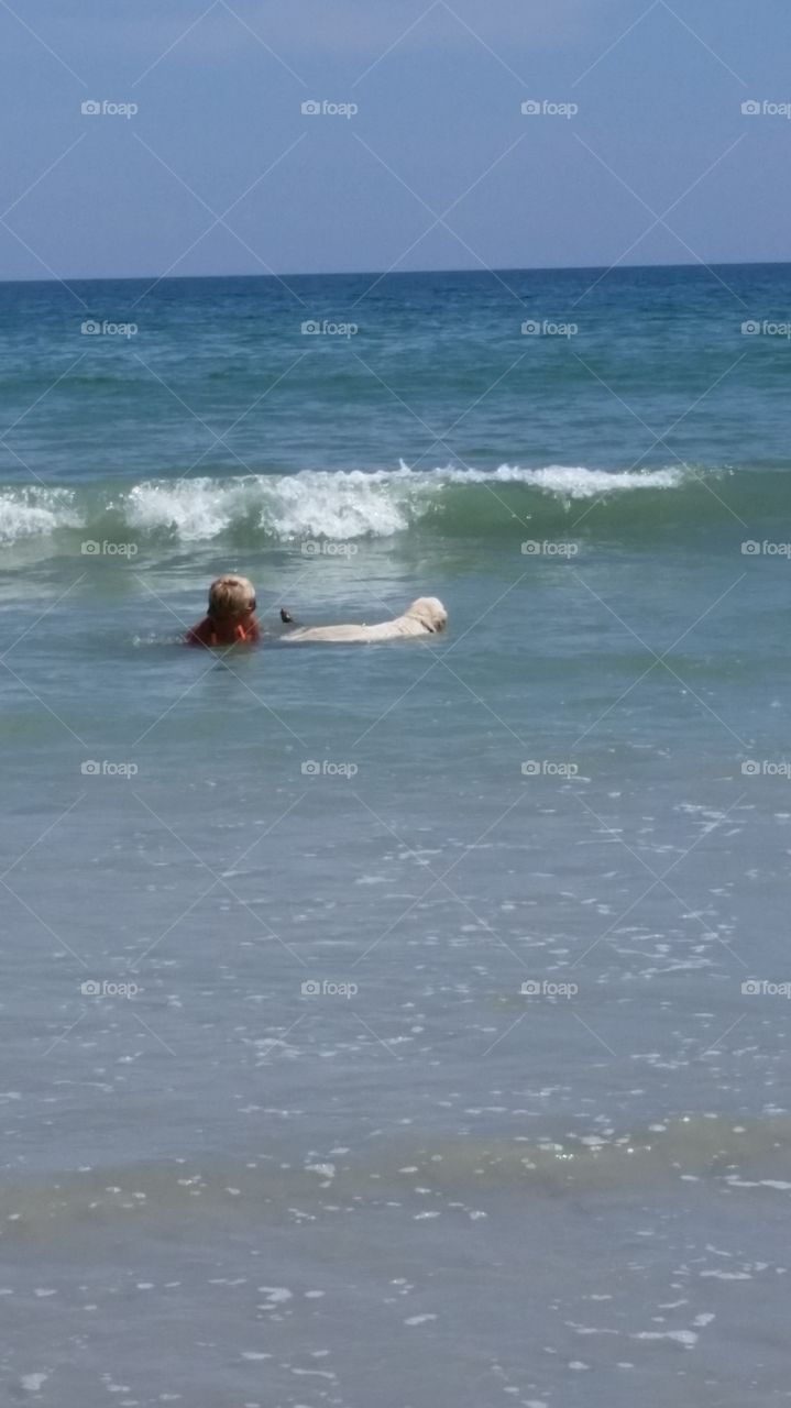 A girl and her dog. swimming in the ocean