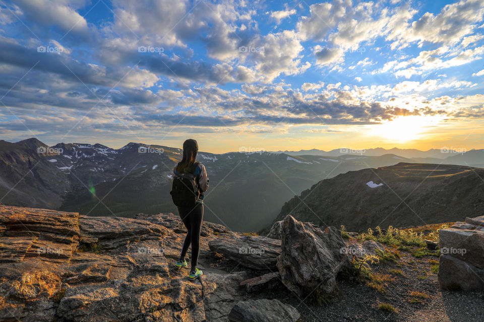 Ready for adventure. Girl with backpack looking into the mountains. Sunset at Rock Cut Overlook, Trail Ridge Road, Rocky Mountain National Park.