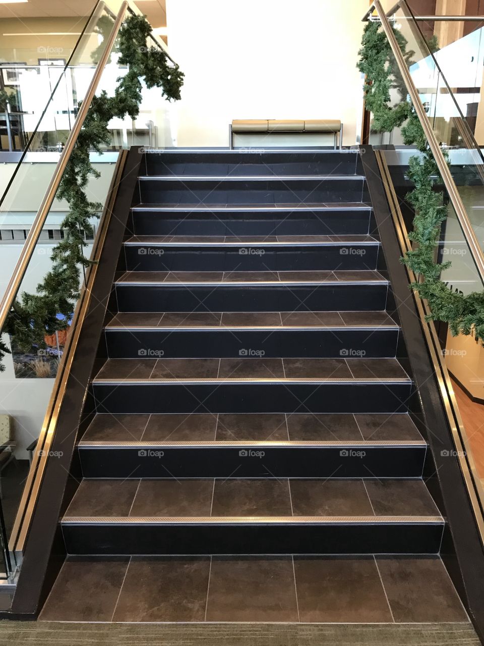 A stairway leading up decorated in strung up garland for the holiday season. 