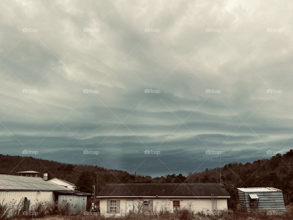 Clouds becoming mountains. A unique cloud striatum on an overcast winter day, with old buildings and foothills at the bottom of the frame.