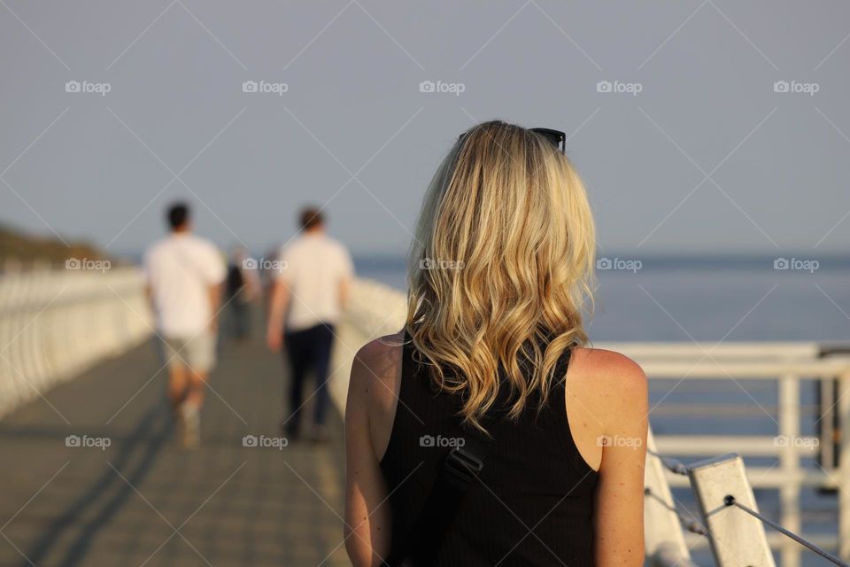 Woman with beautiful blond hair walking on a breakwater 