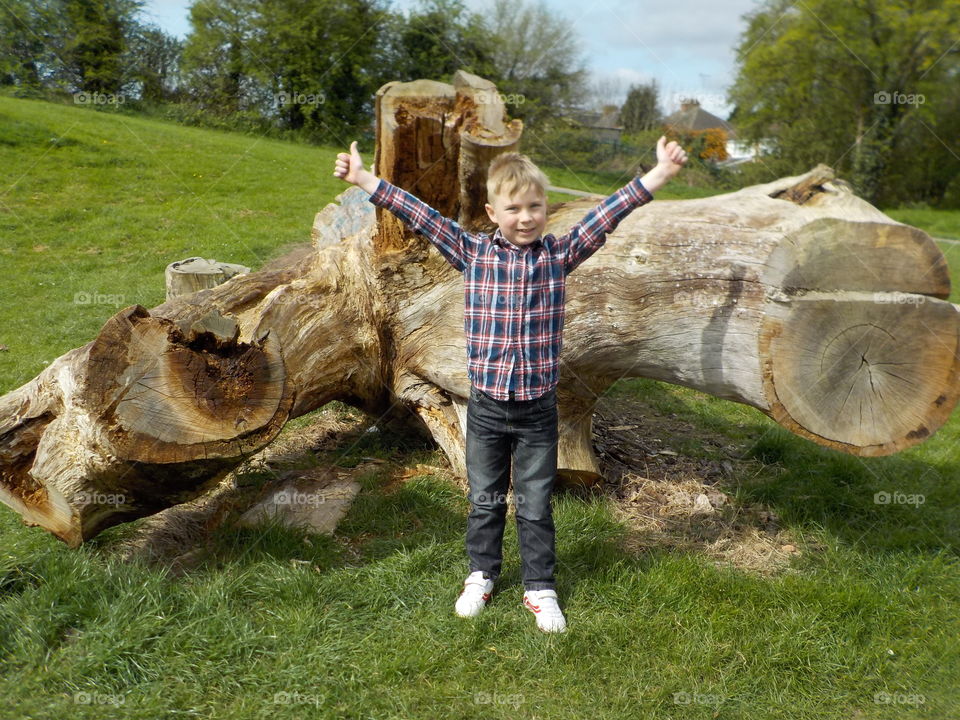 Boy standing on grass raising his arms