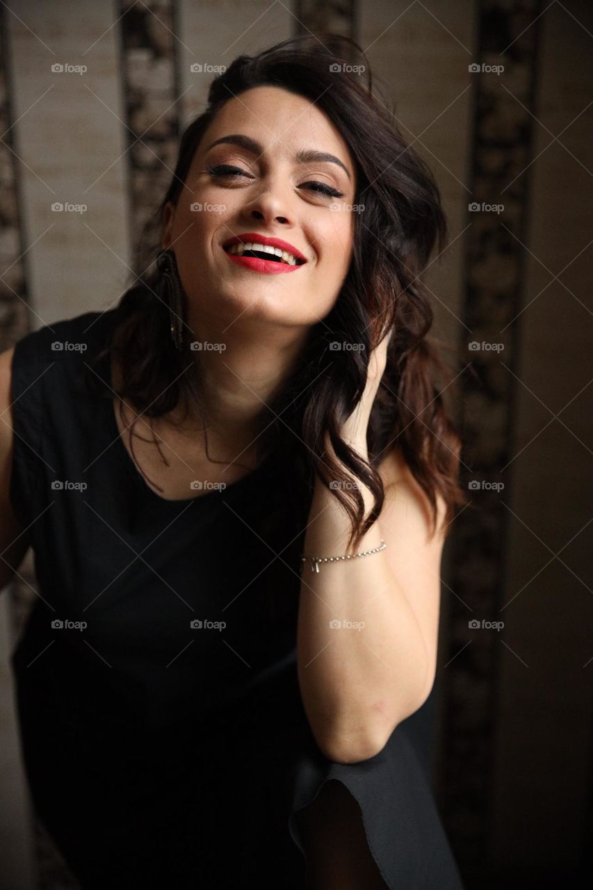 Happy brunnete girl in black dress smile and straighten hair
