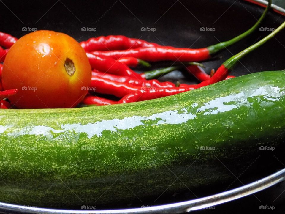 Tomatoes, red chilies and cucumbers on a frying pan