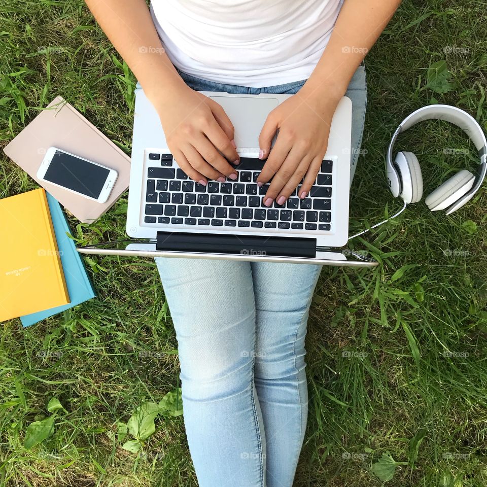 Lifestyle. Girl with laptop working on green grass