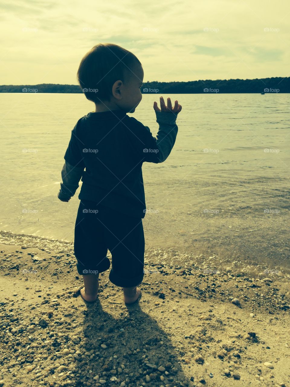 Hi world . A young boy waves at the vast ocean 