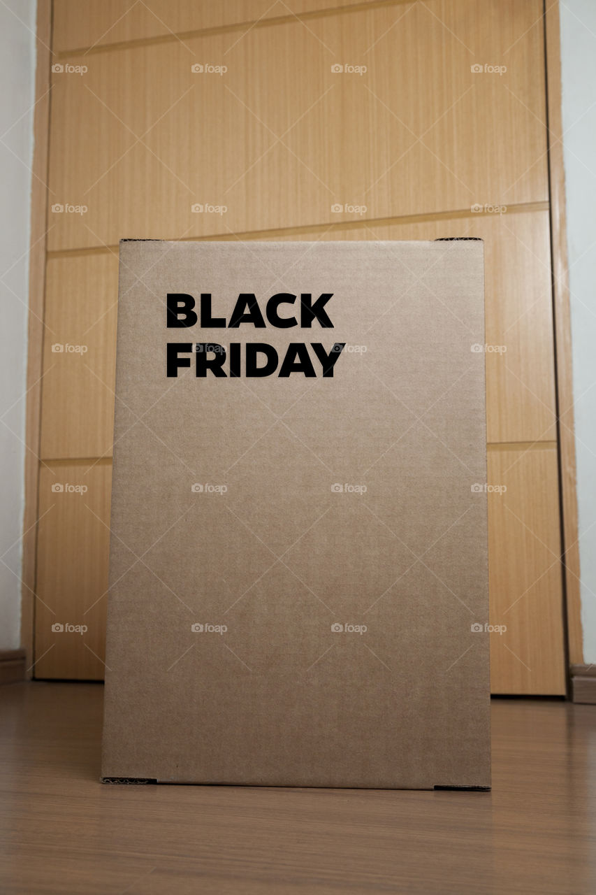 Cardboard box with black friday order written on the box placed on the floor in an empty room with a neutral background. delivery concept. economy concept. black friday concept. shopping concept.