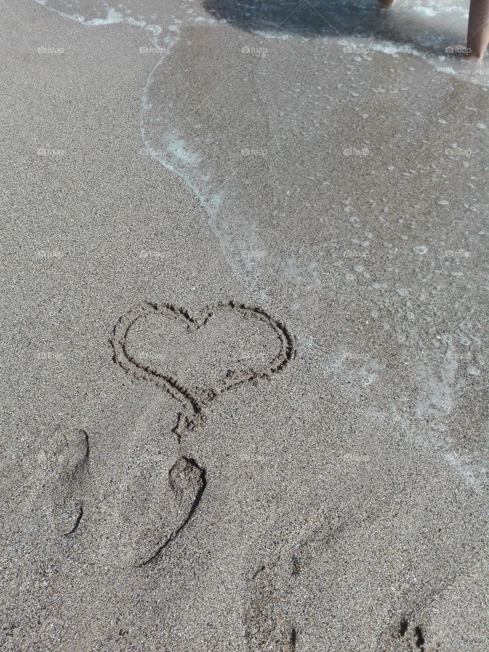 Sand, heart, footprints and waves