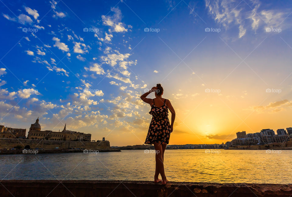 Rear view of a woman against sea at sunset