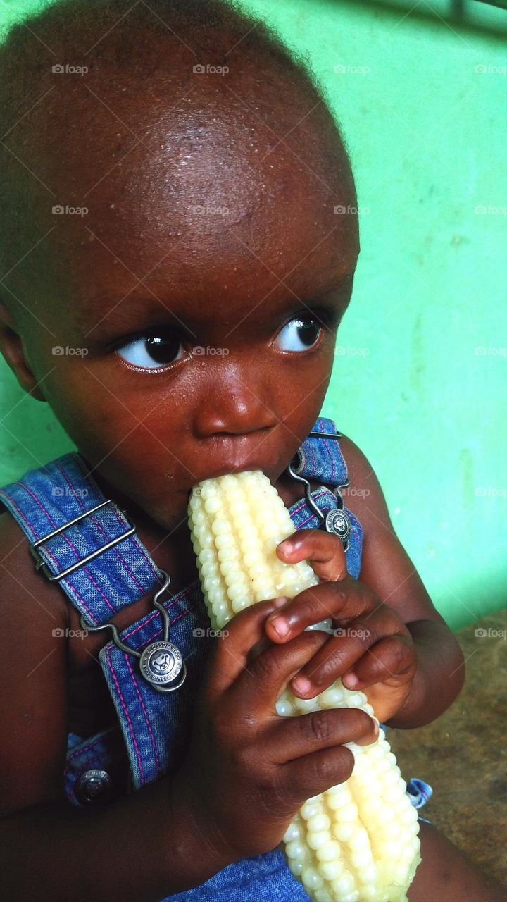 a little kid enjoying a newly harvested corn