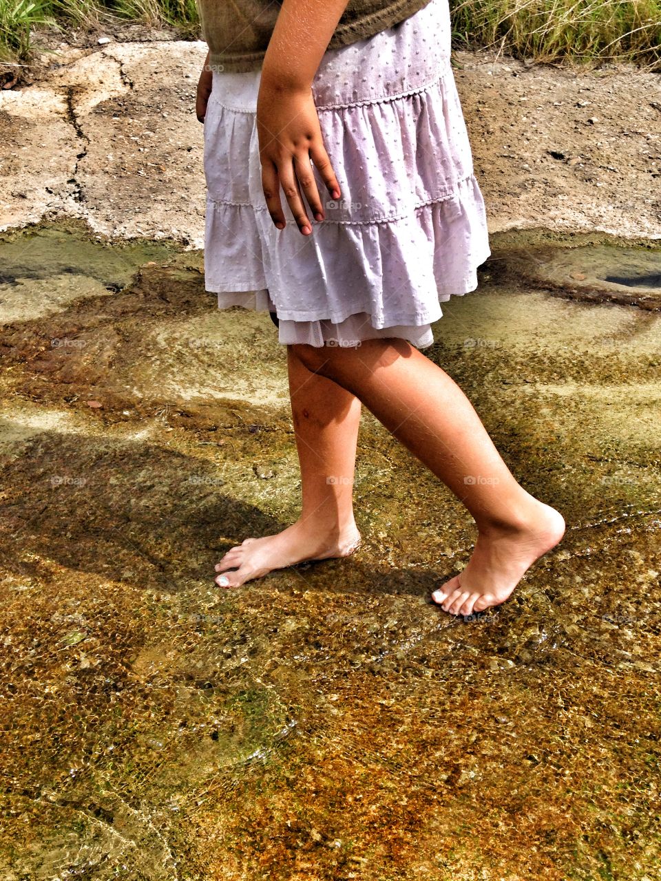 Let's explore. Girl walking in a small stream of water