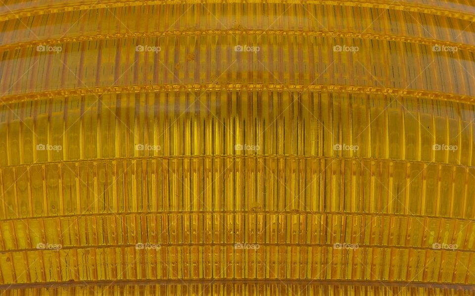 A closeup abstract of a gold colored warning light on top of a vehicle.