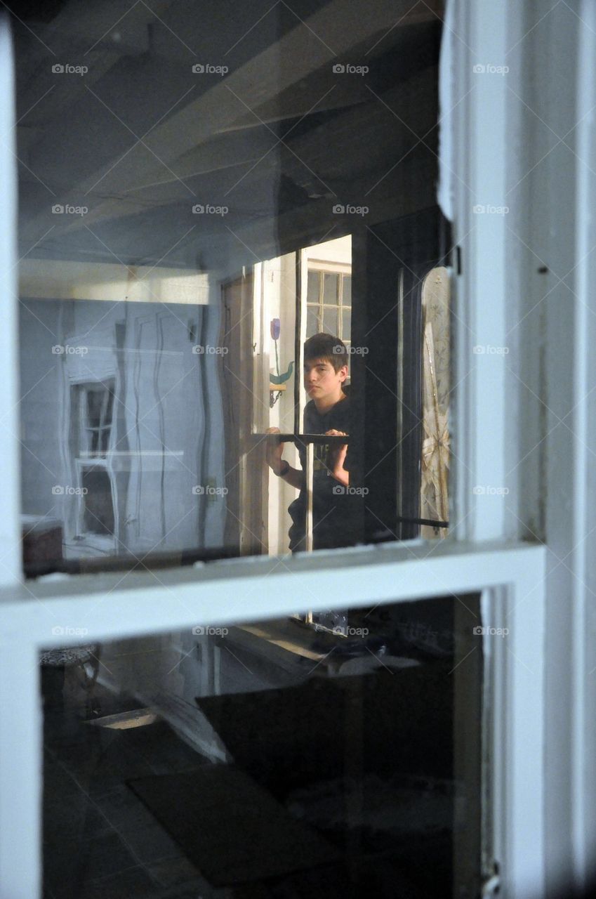 Young man/teen looking though windows of an old house