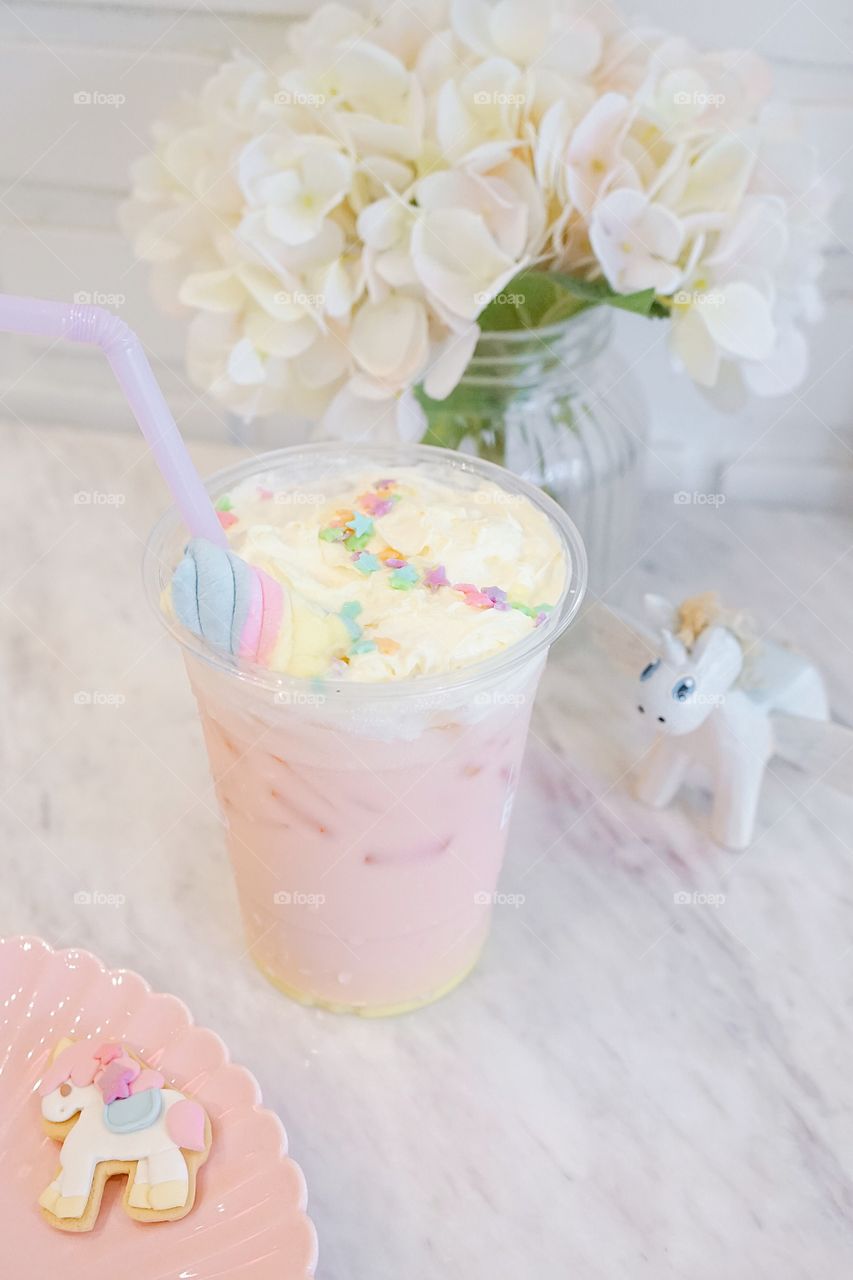 Unicorn drink. Strawberry and caramel milk drink with whipping cream and colorful rainbow starry sugar topping