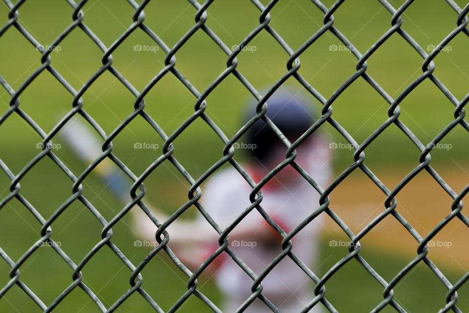 Blurred baseball batter behind chain link fence