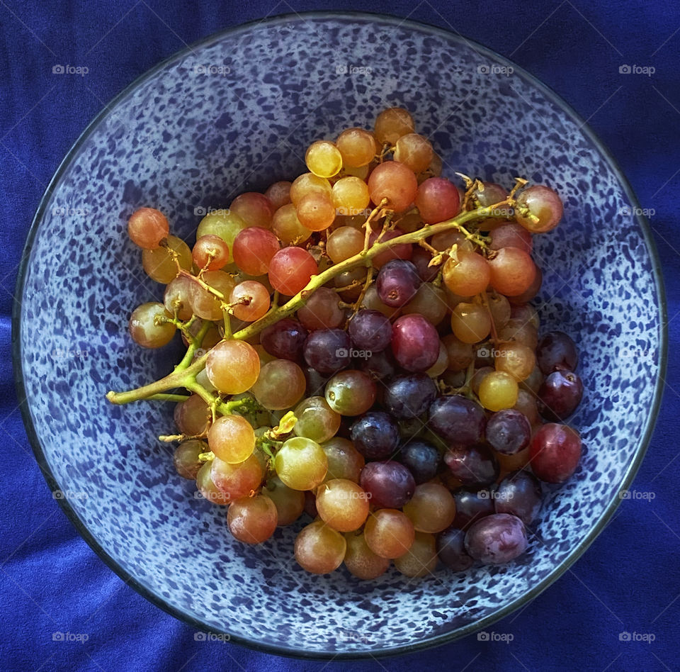 A bowl of grapes on a blue tablecloth 