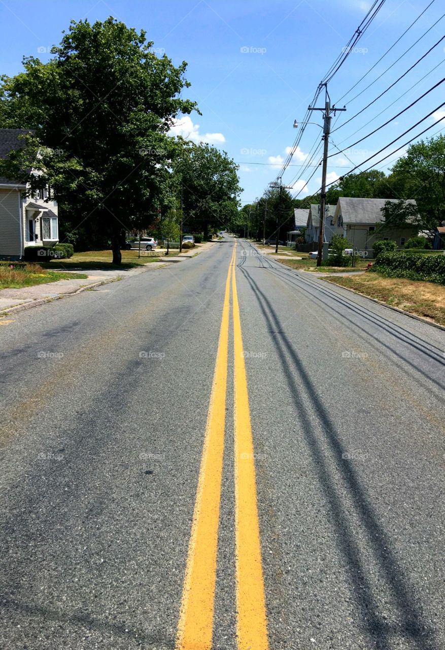 Main street middle of road, no cars, double yellow lines on street. pic in middle of Street, homes on both sides of street, rural roadway.