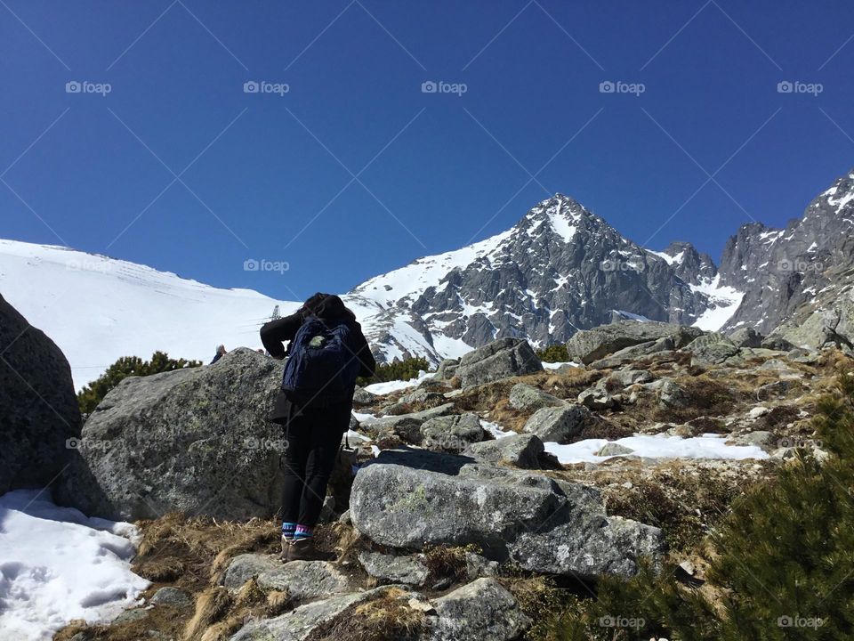Vacation Series: Mountains - A women hikes up the rugged Snow capped mountain top