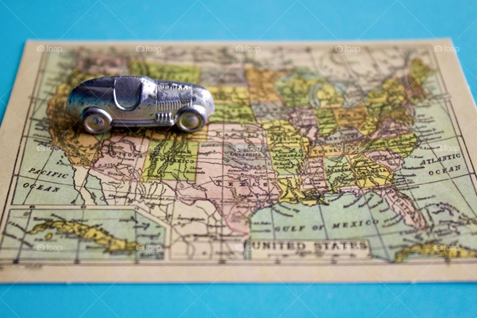 Miniature silver racer heading east on a miniature vintage map of the United States of America against a sky blue background