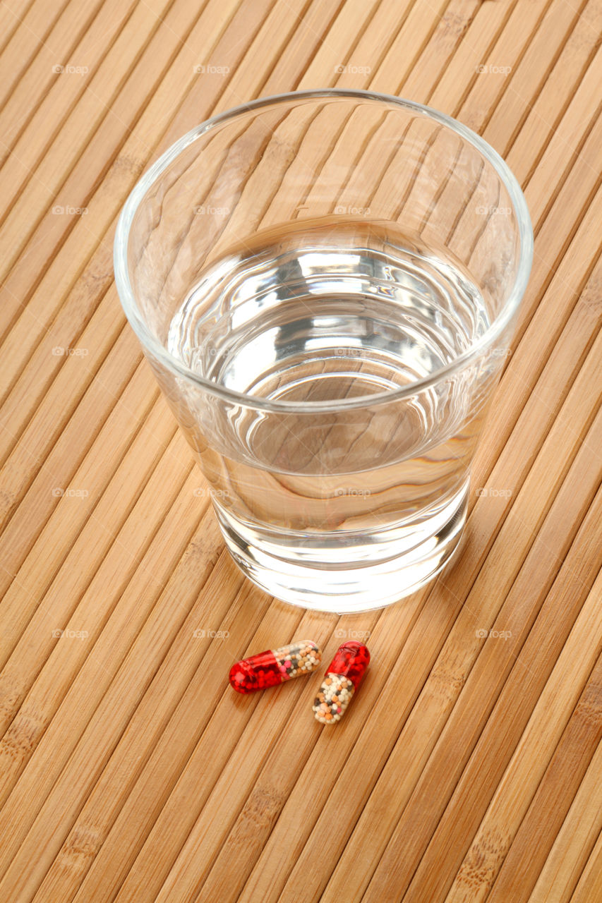 Medicine Capsules and glass on wooden background