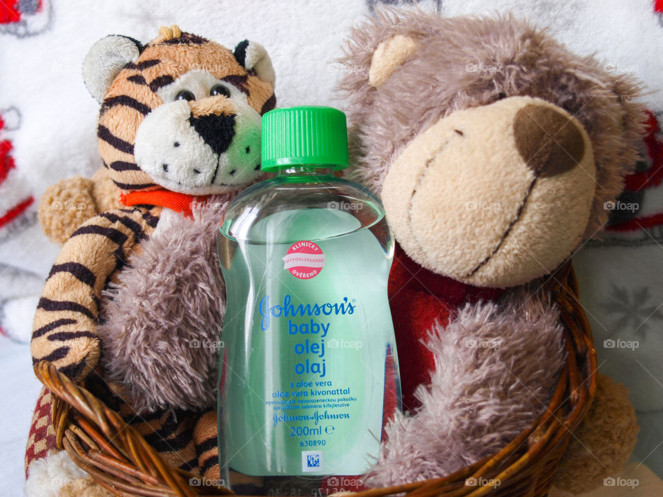 Plush toys in a wooden basket, Johnson's Baby oil in the middle close up.
