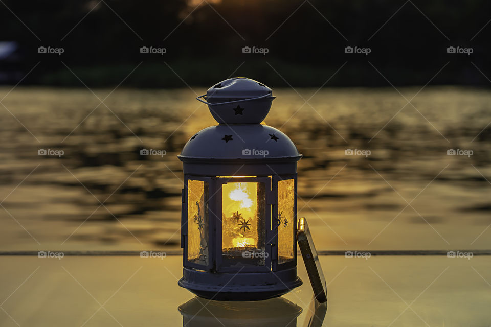 The light of the sun reflecting the water through the lamp and mobile phone on the table.