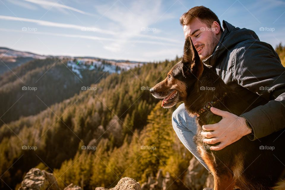Man on a hike with his dog admiring the view over a cliff