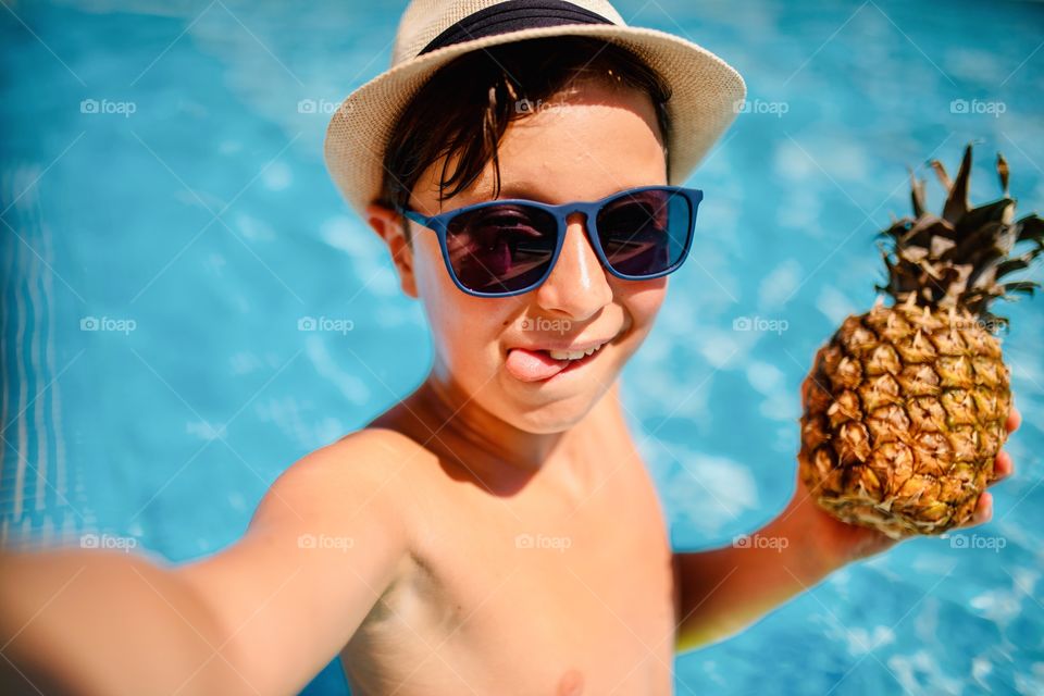 boy makes funny selfie in the pool