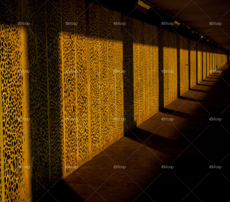 Long shadows are cast against the glass, mosaic walls of Bottle Alley; a seafront, pedestrian underpass in Hastings UK 