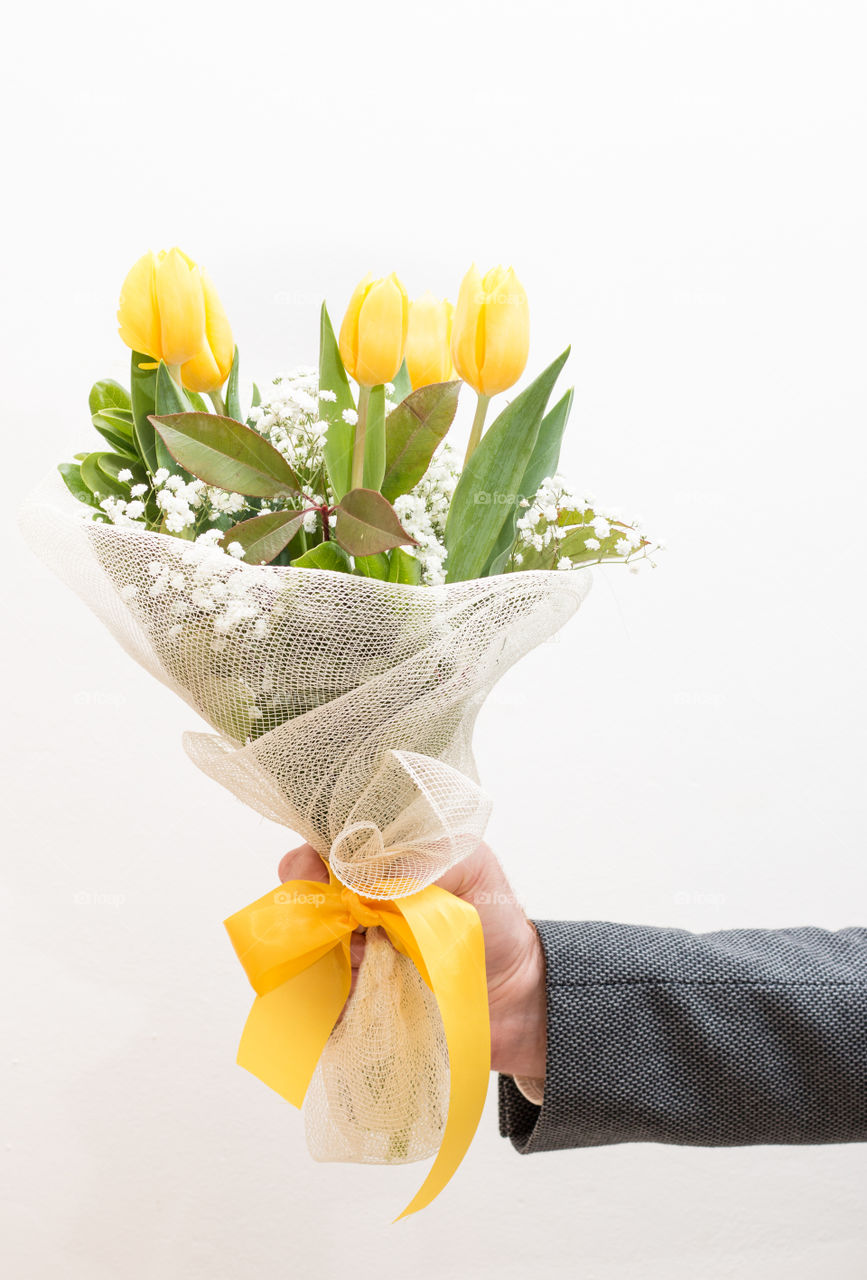 Hand Holding A Bouquet Of Yellow Flowers Tulips, Isolated On White Background
