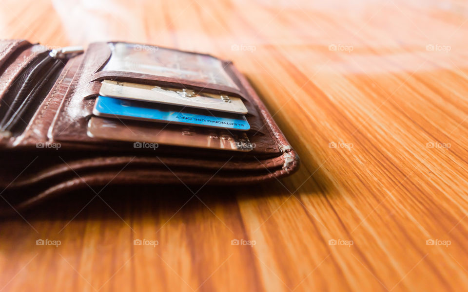 Debit or credit cards in a leather wallet nicely placed at wooden table, studio shot with copy space room for text at right side.