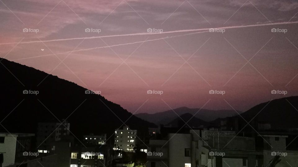 awesome jet contrails crossing the moon at colourful evening